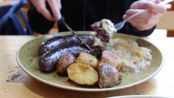 Primo piano donna s mano taglio pezzo di salsiccia di carne cotta sul piatto . — Video Stock