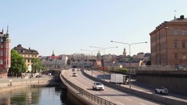 Stockholm, İsveç güneşli bir bahar gününde metro köprüsü altında araba trafiği.