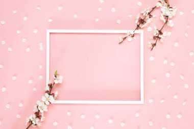 Beyaz çiçekler ile boş çerçeve mockup. Yaratıcı düz, pembe arka planda boş çerçeve mock up ve kiraz ağacı çiçekleri kavramı üst görünümü yatıyordu