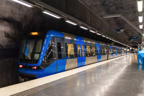 Stockholm, Sweden June 7 2019: Modern illuminated Solna Strand Underground Subway Station with blue moving train.