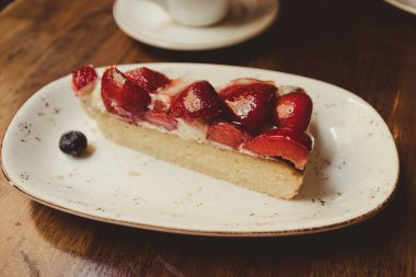 Sevimli bir kafede ahşap Vintage masada kahve latte ile çilek kek yakın. Turistik Yerler