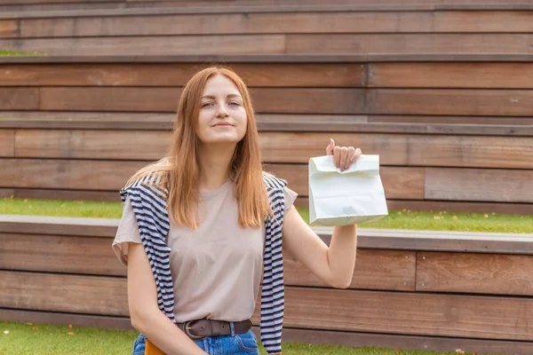 Gelukkige vrouwelijke student houdt een papieren zak — Stockfoto
