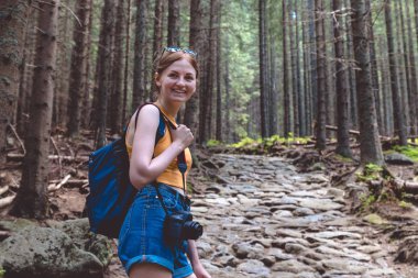 Sırt çantası ve şortlu kadın turist ormanda dolaşıyor