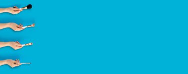 Mavi arka plan üzerinde izole makyaj için fırça ile Kadın el.