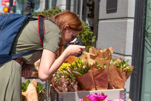 Fiatal lány fotós tesz egy fotót a válogatott virágok csokrok egy üzletben az utcán — Stock Fotó