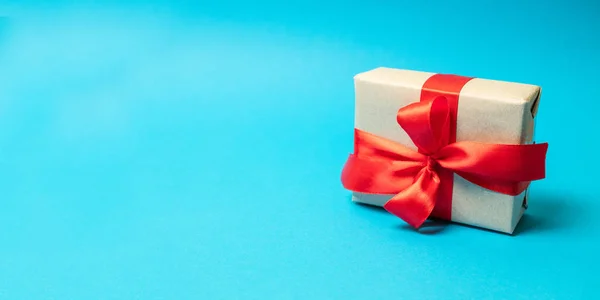 Papel artesanal presente con cinta roja sobre fondo azul. Tiro cuadrado — Foto de Stock