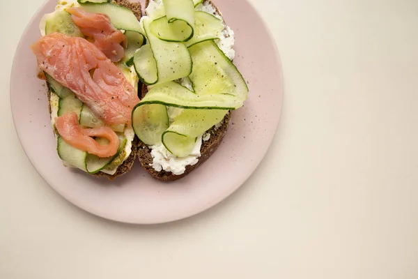 Sandwich con salmón, pepino, queso y pan de centeno sobre fondo blanco. Concepto de dieta y obesidad —  Fotos de Stock