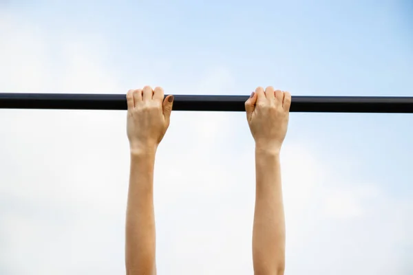 Girl passes the standards for pulling up on a horizontal bar in the park sunny day. — Stock Image Girl passes the standards for pulling up on a horizontal bar in the park sunny day. Stock Photo