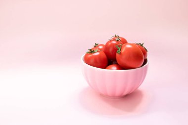 Pembe bir arka plan üzerinde olgun kırmızı domates ile pembe seramik kase. Sağlıklı Diyet Vitaminler Bio Foods