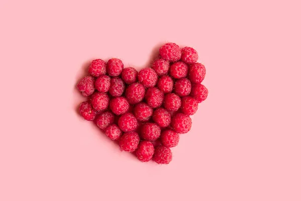 Framboises rouges en forme de coeur sur fond rose — Photo