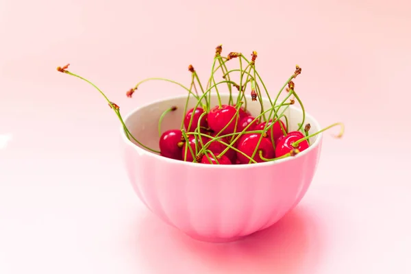 Baya de cereza sobre un fondo rosa en una taza de color rosa, vista superior. Concepto de fertilización . —  Fotos de Stock