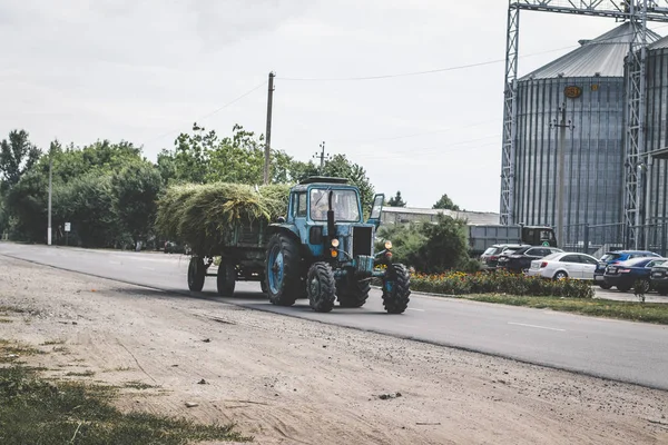 Tracteur avec chariot à foin. Tracteur tirant une remorque avec du foin sur un pont — Photo