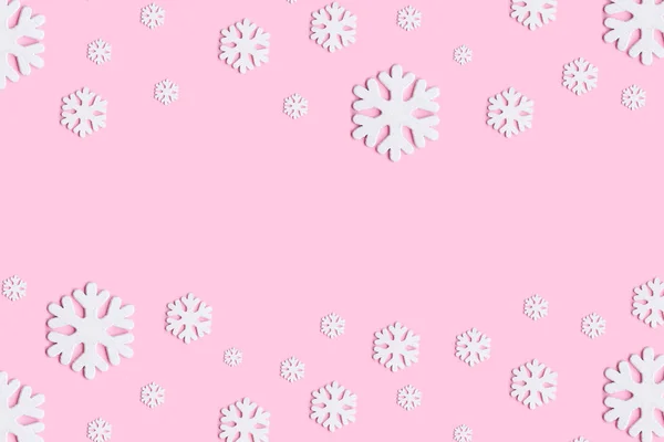 Noel veya kış kompozisyonu. Pastel pembe arka plan üzerinde kar tanelerinden yapılmış desen. — Stok fotoğraf