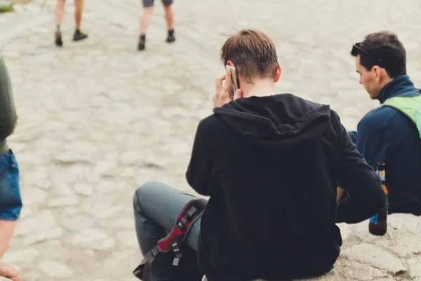 Ein junger Mann im schwarzen T-Shirt benutzt ein Smartphone und telefoniert. — Stockfoto