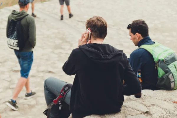 Ein junger Mann im schwarzen T-Shirt benutzt ein Smartphone und telefoniert. — Stockfoto