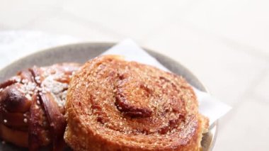 Bir sokak kafede bir masada gri bir seramik plaka üzerinde taze şeker tarçın rulo.