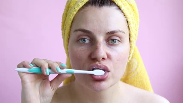 Chica joven en una toalla después de una ducha se cepilla los dientes. Autocuidado matutino — Vídeos de Stock