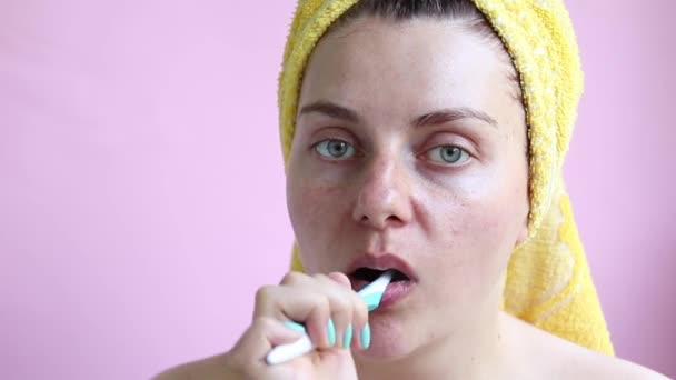 Young girl in a towel after a shower brushes her teeth. Morning self-care — Stockvideo