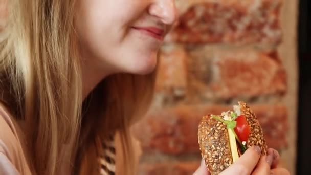 Женщина ест гамбургер в кафе — стоковое видео