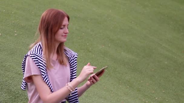 Chica joven hablando en el teléfono móvil sentado en un banco en un parque — Vídeos de Stock