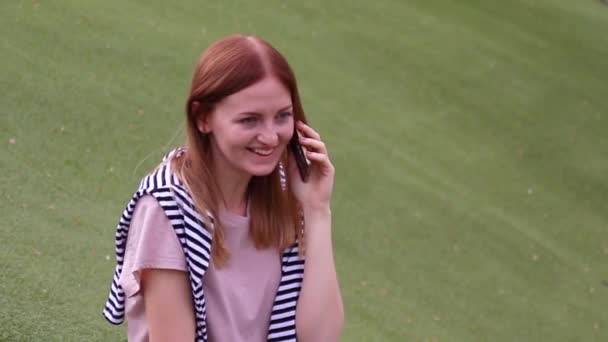 Jeune fille parlant sur un téléphone portable assis sur un banc dans un parc 