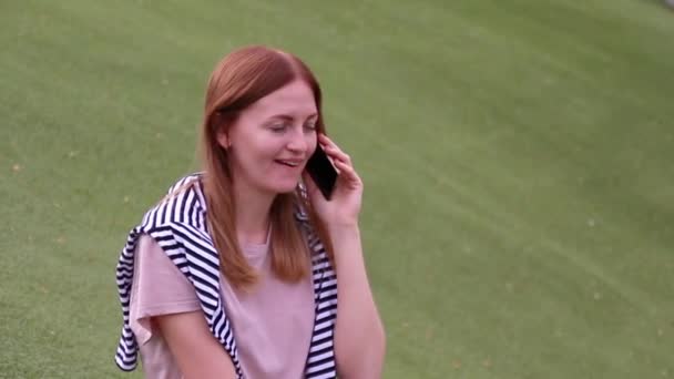 Jeune fille parlant sur un téléphone portable assis sur un banc dans un parc 