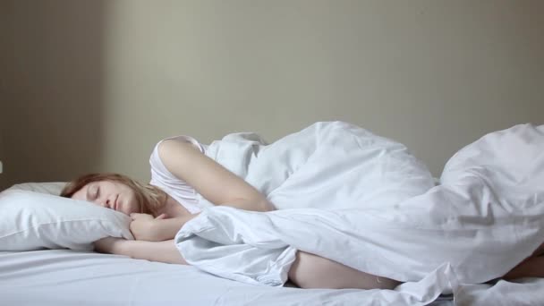 Linda loira lentamente acordar de manhã, se estende e se levanta da cama . — Vídeo de Stock