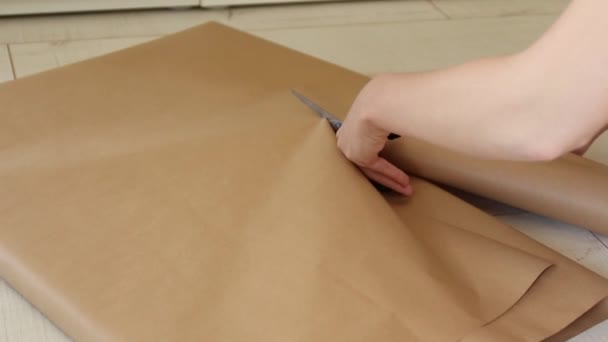 Frauenhände schnitten handwerkliches Geschenkpapier. Vorbereitung auf ein neues Jahr, Geburtstag oder Weihnachten — Stockvideo