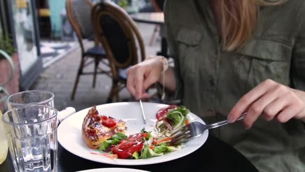 As mãos femininas cortam uma fatia de pizza em uma chapa em um café de rua acolhedor . — Vídeo de Stock