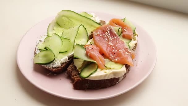 Otevřený sendvič s rybami a zeleninou s růžovou keramickou deskou — Stock video