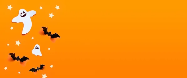 Composizione vacanze autunnali. Concetto di celebrazione di Halloween con pipistrelli, fantasma, ragnatela, stelle su uno sfondo arancione . — Foto Stock