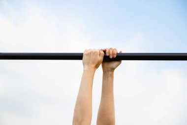 Kadın elleri mavi gökyüzüne karşı yatay çubuk tutun.