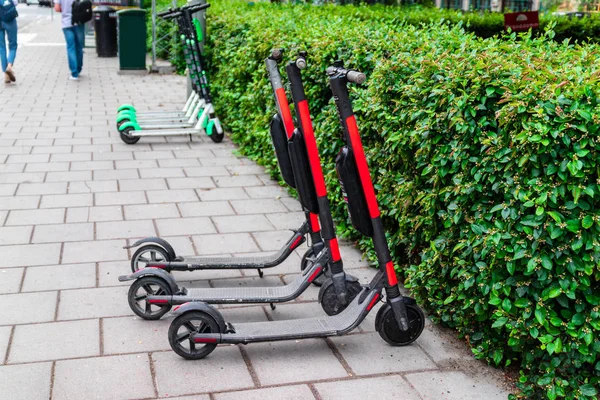 Ett antal elbilar förbereder sig för en åktur på skotrar med batterier i stadens centrum på trottoaren. Elektriska stadstransporter. — Stockfoto