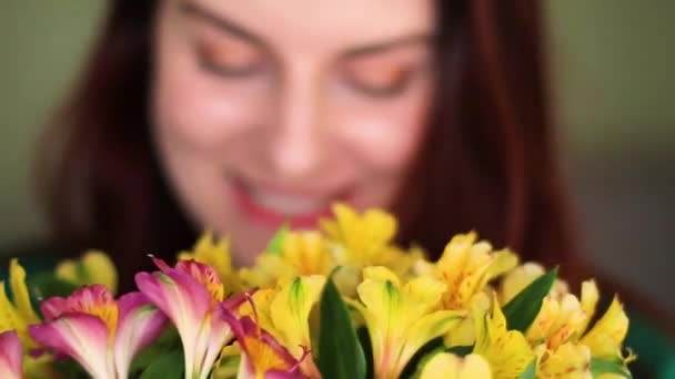 Jolie fille renifle un bouquet et regarde la caméra . — Video