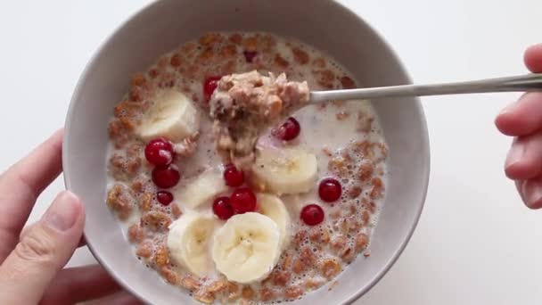 Kvinnlig hand stör havregryn med bär och en banan i en tallrik. Frukost koncept — Stockvideo