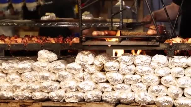 Gotowanie mięsa i na grill w kawiarni. Ręcznie używać Szczypce do toczenia mięsa na grilla. Kiełbaski, kurczak, wędliny są smażone na grilla. — Wideo stockowe