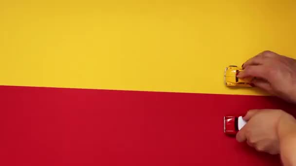 Kleine rode en gele speelgoed auto's gaan op een geel-rode achtergrond, bovenaanzicht — Stockvideo