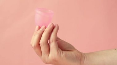 Pembe bir arka plan üzerinde kadın elinde pembe adet fincan.