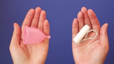 Genç kadın elleri kadınsı hijyen ürünleri adet fincan ve tamponlar farklı tutarak.