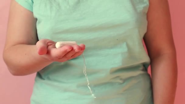 Die weibliche Hand hält einen Tampon auf rosa Hintergrund. Eisprung, Menstruationszyklus Konzept. Frauen Gesundheit Menstruation. — Stockvideo