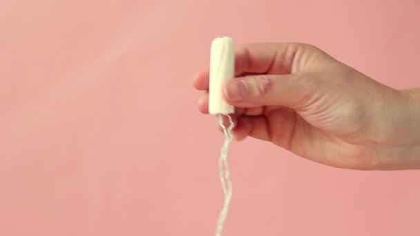 Female hand shows a tampon on a pink background. — Stock Video