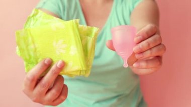 Kadın elleri kadınhijyen ürünleri adet fincan ve sıhhi peçete farklı tutarak. Sıfır atık kavramı.