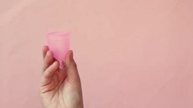 Bu dönemde alternatif kadınsı hijyen ürünü. Adet bardağı tutan genç kadının yakından görünümü