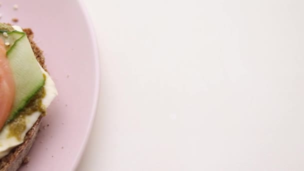 Відкритий бутерброд з рибою та овочами з рожевою керамічною тарілкою — стокове відео
