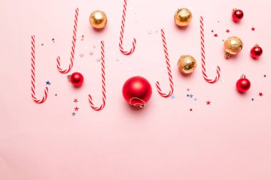 Modern Yeni Yıl ya da çizgili şekerli Noel afişi, altın ve kırmızı toplar, pembe arka planda parlayan yıldız dekoru.