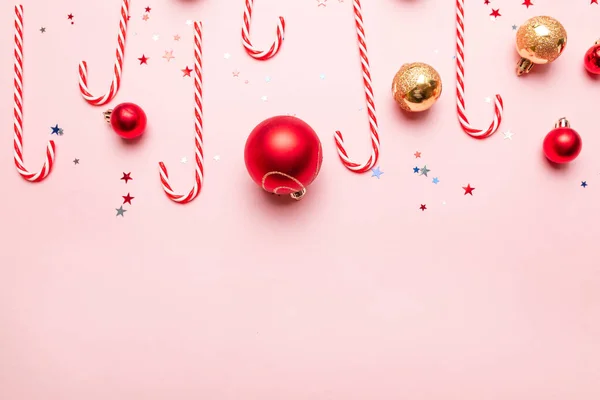 Capodanno sfondo di Natale con bastoncini di zucchero, oro e palline rosse su sfondo rosa. Modello modello modello biglietto di auguri disegno del testo — Foto Stock