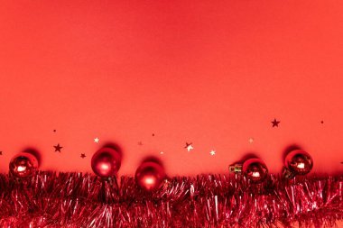 Noel ve Yeni Yıl arkaplanı kırmızı parlak ve mat toplarıyla, kırmızı arka planda parıldayan yıldızlar.