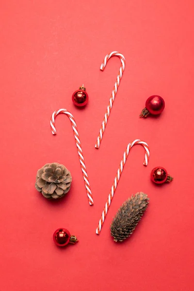 Kreative Komposition mit Tannenzapfen, roten Kugeln auf rotem Hintergrund von oben. flache Komposition für Weihnachten oder Neujahr — Stockfoto