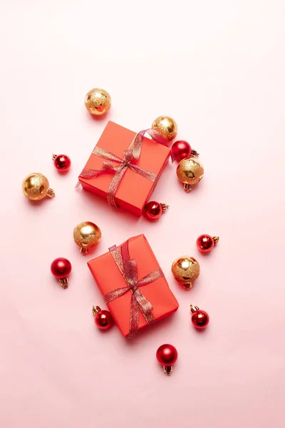 Caja de regalo de Navidad con cinta de satén, oro y bolas rojas sobre un fondo rosa. Invierno, concepto de año nuevo. Plano, vista superior, espacio para copiar — Foto de Stock