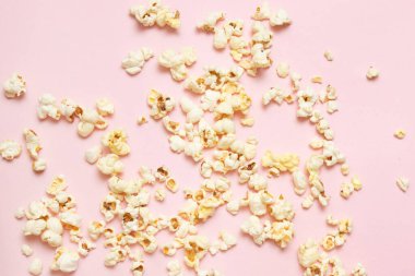 Sinema, sinema ve eğlence konsepti. Pembe arka planda lezzetli patlamış mısır desenlerinin üst görünümü.